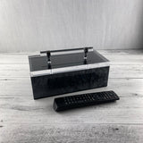 acrylic storage box on a wooden table being used for a remote control organizer holder.
