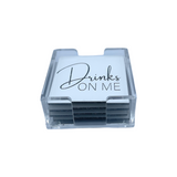 solid white coaster set with clear acrylic holder, back of coaster and DRINKS ON ME in silver sparkle