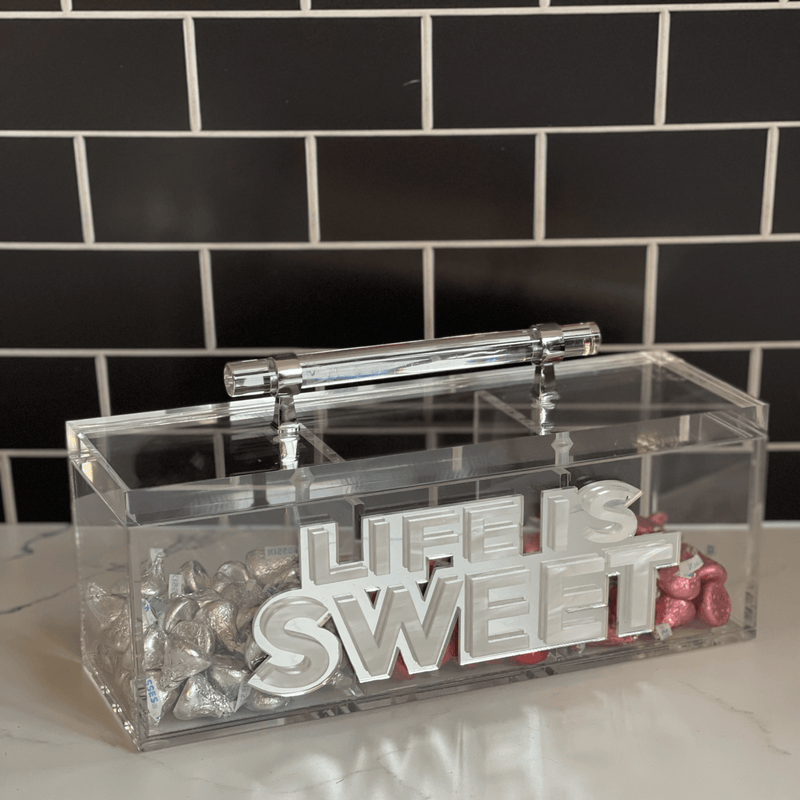  LIFE IS SWEET candy box on a kitchen counter with silver, red and pink chocolate kisses in the different compartments.