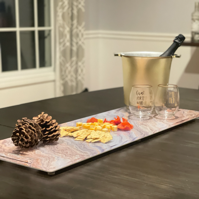 long charcuterie cheeseboard on dining room table with cheese , crackers and wine displayed