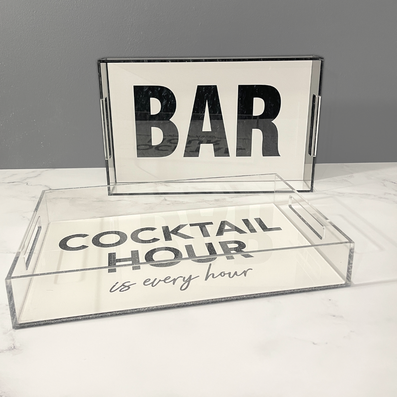 Acrylic white and clear serving bar trays that say "BAR" in black and "Cocktail Hour is every hour" on black glitter.