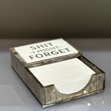 acrylic notepad with the words SH*T I MIGHT FORGET imprinted on a silver marble acrylic holder displayed on a desk.