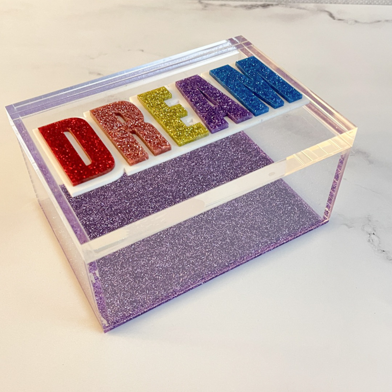 DREAM clear acrylic decor box with purple sparkle bottom and colorful acrylic lettering on marble dresser