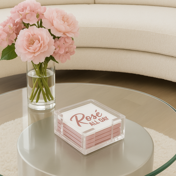 clear acrylic coaster set with pink coasters printed with the phrase Rose ALL DAY displayed on a modern glass coffee table with fresh flowers in a contemporary living room
