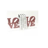 Custom acrylic bookends that spell LOVE in pink sparkle finish, styled on a shelf holding books