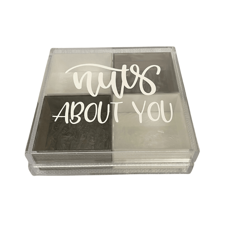 a clear acrylic tray on a rotating base with 4 colored boxes and a lid that has a sticker that says nuts ABOUT YOU