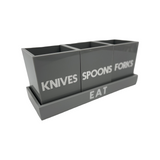 grey solid utensil caddy on tray that says EAT with 3 cups saying FORKS, KNIVES and SPOONS , white etched lettering
