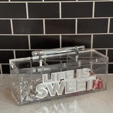 image of LIFE IS SWEET candy box on a kitchen counter with silver, red and pink chocolate kisses in the different compartments.