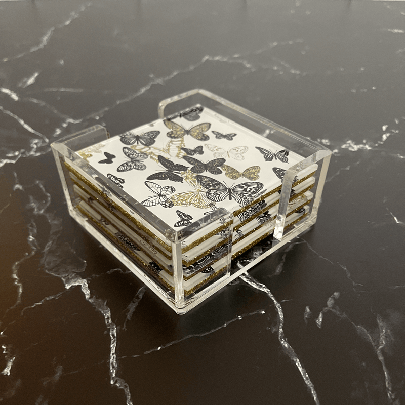 gold butterfly coasters on a black & white marble table.